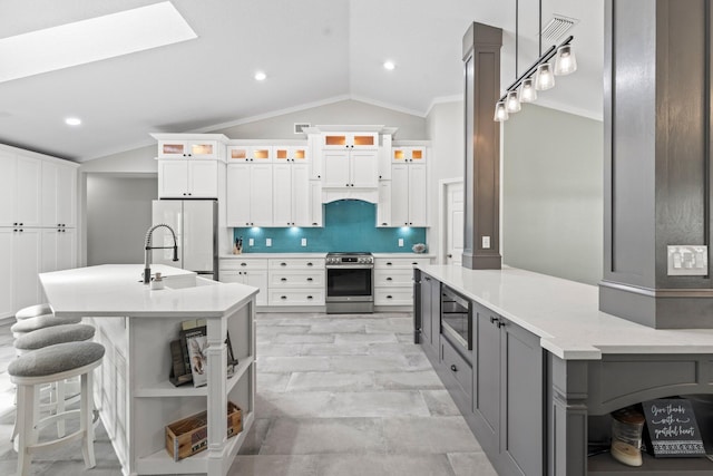 kitchen featuring tasteful backsplash, vaulted ceiling, white fridge, white cabinets, and stainless steel stove