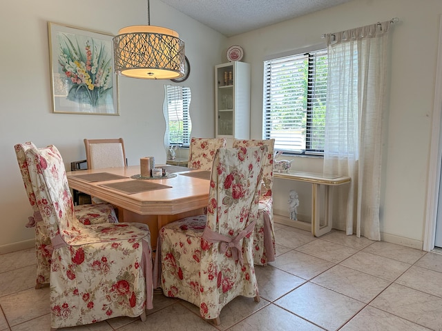 dining area featuring light tile patterned floors and a textured ceiling