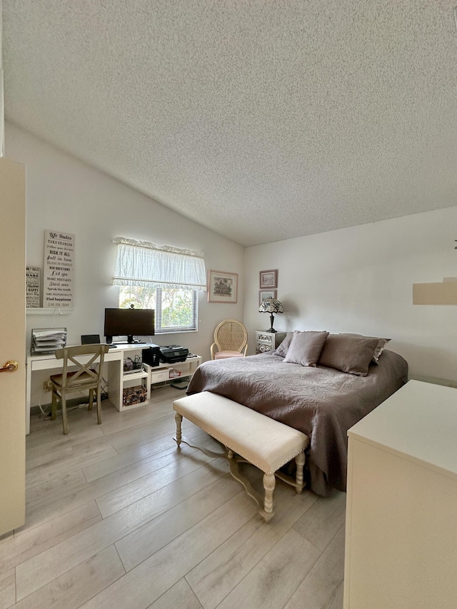 bedroom featuring a textured ceiling, light hardwood / wood-style floors, and lofted ceiling