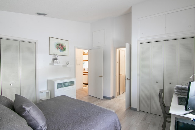 bedroom featuring multiple closets and light hardwood / wood-style flooring