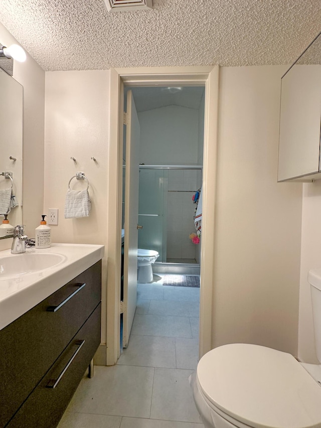 bathroom with an enclosed shower, vanity, toilet, and tile patterned flooring