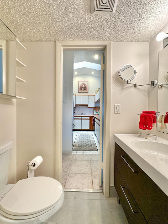 bathroom featuring tile patterned flooring, vanity, toilet, and a textured ceiling