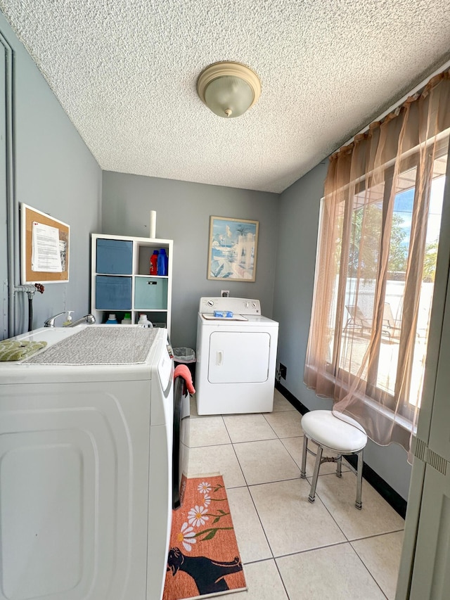 washroom with washing machine and dryer, light tile patterned floors, and a textured ceiling