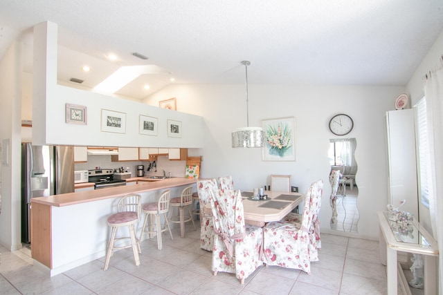 dining space featuring sink, light tile patterned flooring, and lofted ceiling