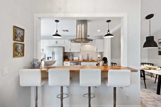 kitchen featuring a kitchen bar, appliances with stainless steel finishes, white cabinetry, and pendant lighting