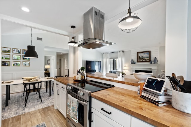 kitchen with butcher block countertops, electric stove, island range hood, and hanging light fixtures