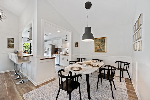 dining space featuring sink, lofted ceiling, and light hardwood / wood-style flooring