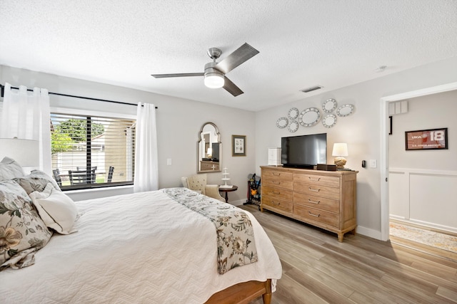 bedroom featuring ceiling fan, light wood-type flooring, and a textured ceiling