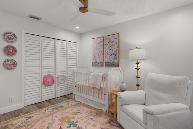 bedroom featuring hardwood / wood-style flooring, ceiling fan, a textured ceiling, and a nursery area