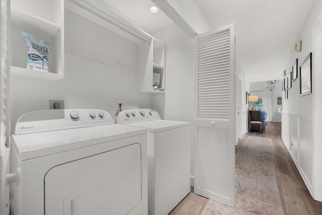 clothes washing area featuring separate washer and dryer and light hardwood / wood-style flooring