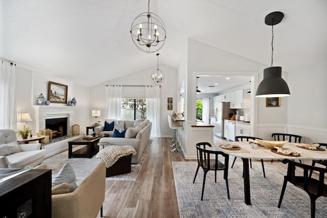 living room featuring a notable chandelier, vaulted ceiling, and light wood-type flooring