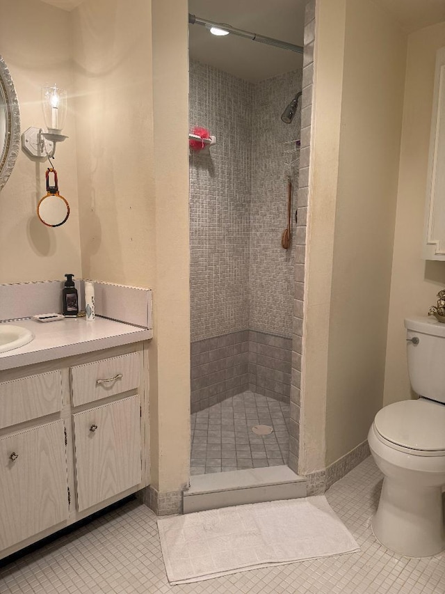 bathroom featuring a shower, vanity, toilet, and tile patterned flooring