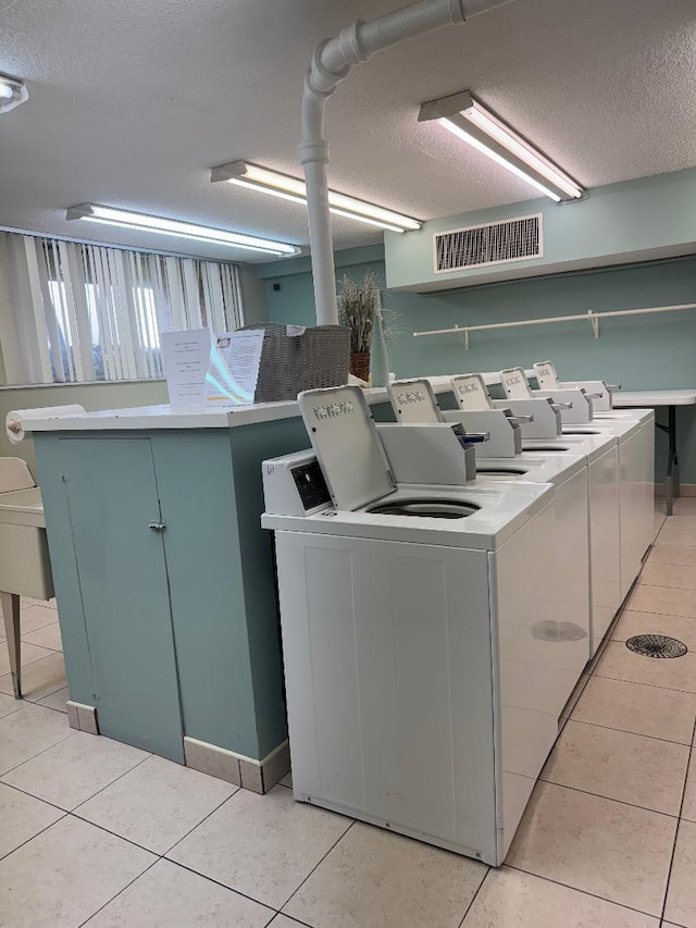 laundry room with light tile patterned floors, a textured ceiling, and separate washer and dryer