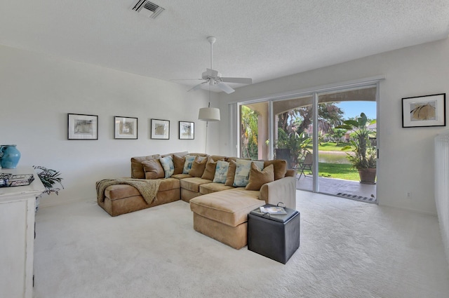 living room featuring ceiling fan, a textured ceiling, and light carpet