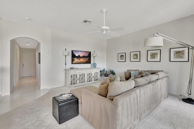 living room with ceiling fan, light tile patterned floors, and a textured ceiling