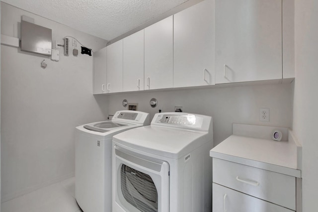 laundry room featuring washer and clothes dryer, cabinets, and a textured ceiling