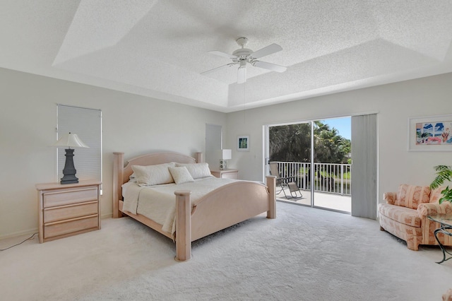 bedroom with a tray ceiling, access to exterior, ceiling fan, and light colored carpet