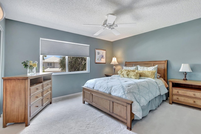 bedroom featuring ceiling fan, light colored carpet, and a textured ceiling