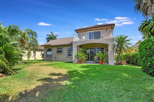 rear view of property featuring a lawn and a balcony