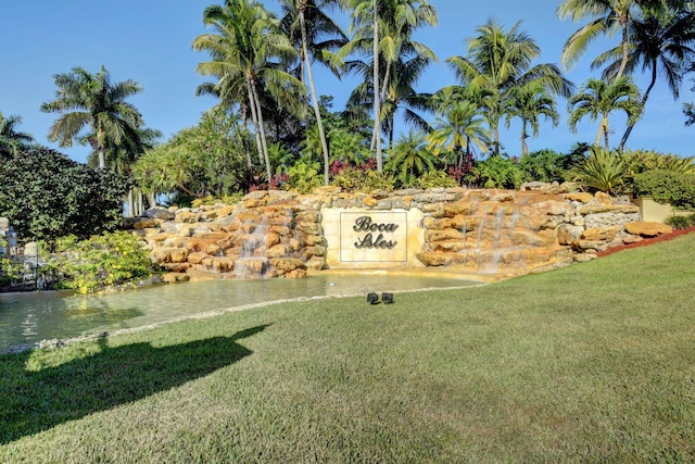 community sign with a water view and a yard