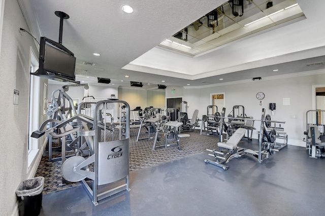 gym with dark carpet, crown molding, and a tray ceiling