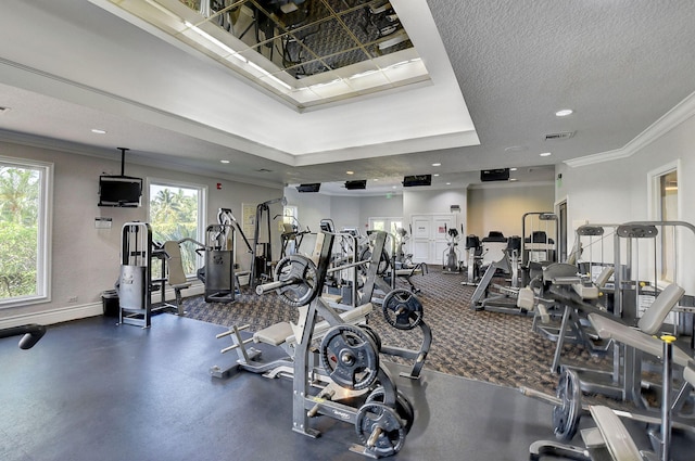 workout area with a textured ceiling, a raised ceiling, and ornamental molding