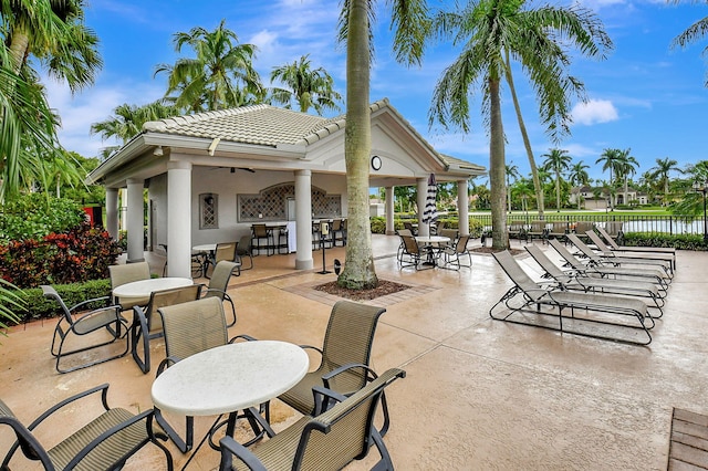 view of patio featuring a water view, ceiling fan, and a bar