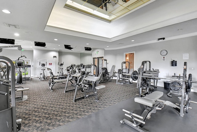 exercise room featuring a tray ceiling, dark carpet, and ornamental molding