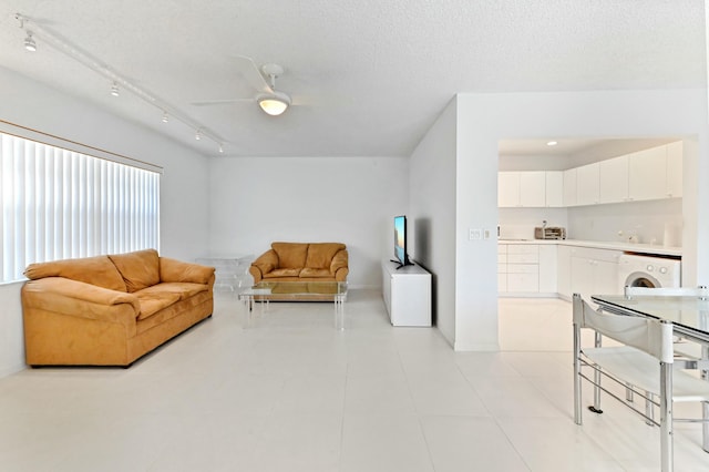 tiled living room with a textured ceiling, washer / clothes dryer, track lighting, and ceiling fan