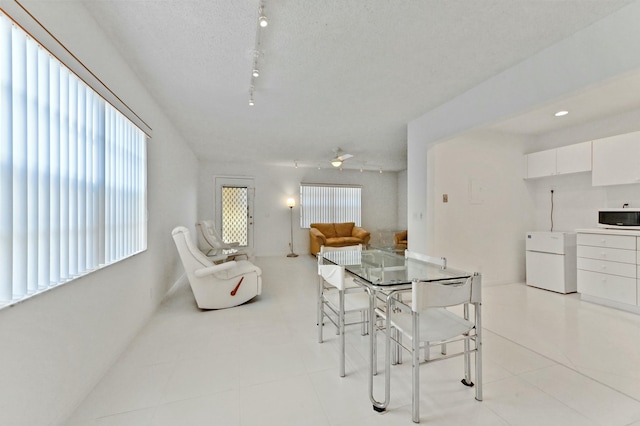 dining area featuring a textured ceiling, ceiling fan, light tile patterned flooring, and track lighting