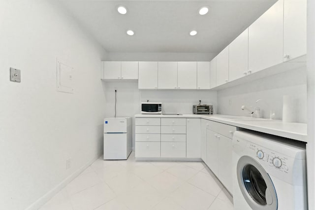 clothes washing area with sink, light tile patterned floors, and washer / dryer