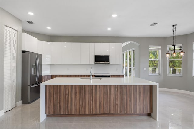 kitchen featuring pendant lighting, a center island with sink, white cabinetry, and appliances with stainless steel finishes