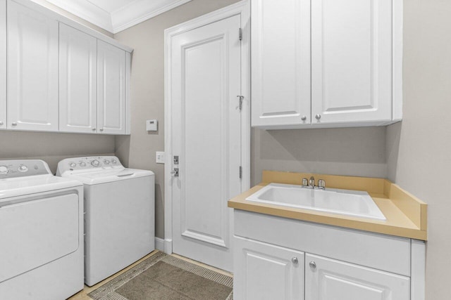 laundry area with cabinets, washing machine and dryer, crown molding, and sink