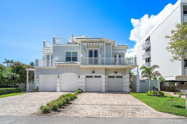 view of front of home with an attached garage, a balcony, fence, driveway, and stucco siding