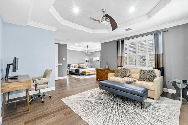 living room with a raised ceiling, crown molding, wood-type flooring, and ceiling fan with notable chandelier