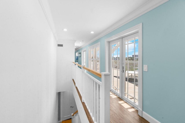 corridor with wood-type flooring, ornamental molding, a wealth of natural light, and french doors