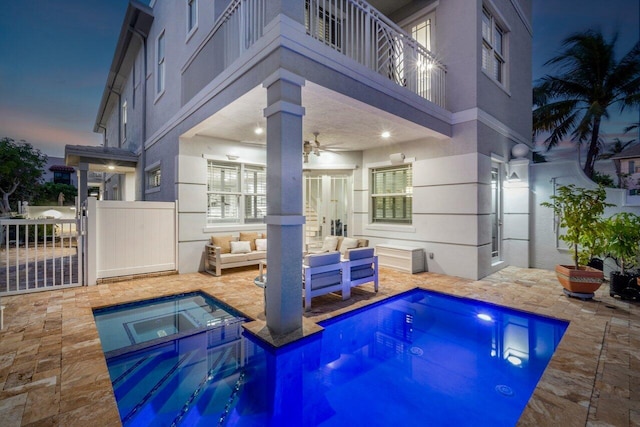 pool at dusk featuring ceiling fan, an in ground hot tub, and a patio