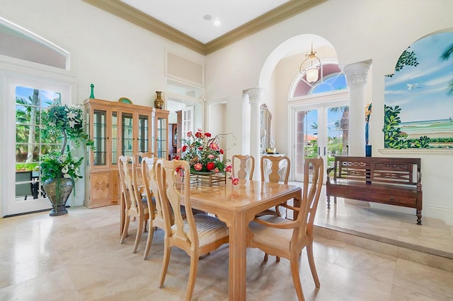 dining space with french doors, decorative columns, crown molding, and a high ceiling