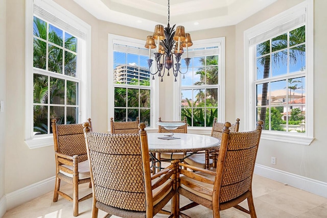 dining space with light tile patterned floors, a tray ceiling, and an inviting chandelier