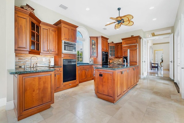 kitchen featuring backsplash, paneled built in fridge, dark stone countertops, a center island, and oven