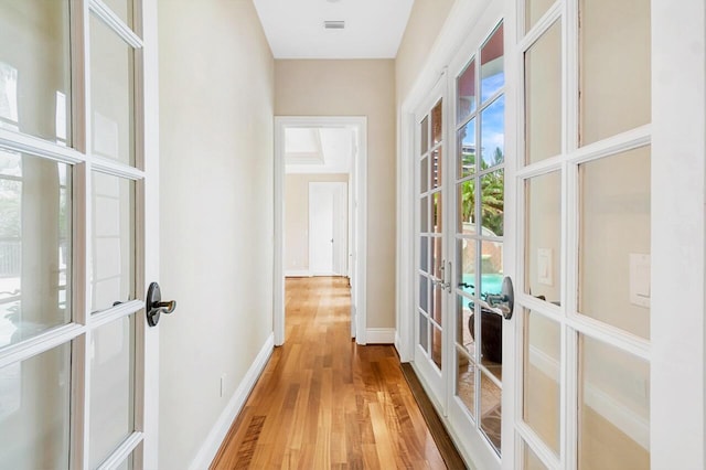 hallway featuring french doors and light hardwood / wood-style floors