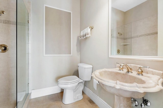 bathroom with a tile shower, sink, tile patterned flooring, and toilet