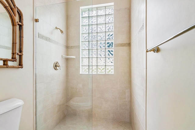 bathroom featuring a tile shower and toilet