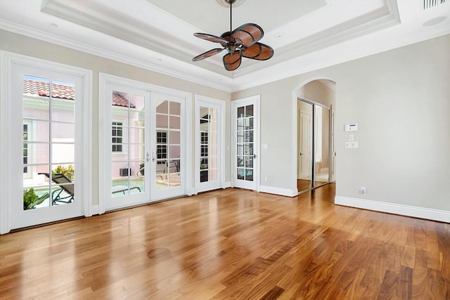 unfurnished room with french doors, a raised ceiling, crown molding, ceiling fan, and light wood-type flooring