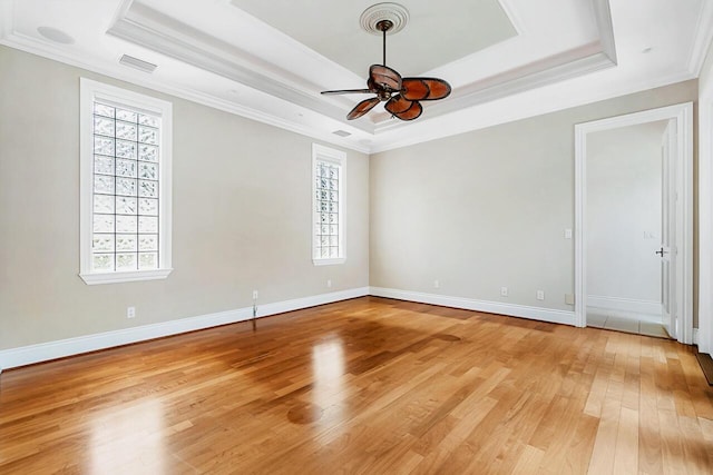 unfurnished room featuring light wood-type flooring, a raised ceiling, ceiling fan, and crown molding