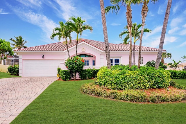 mediterranean / spanish home featuring a garage and a front lawn