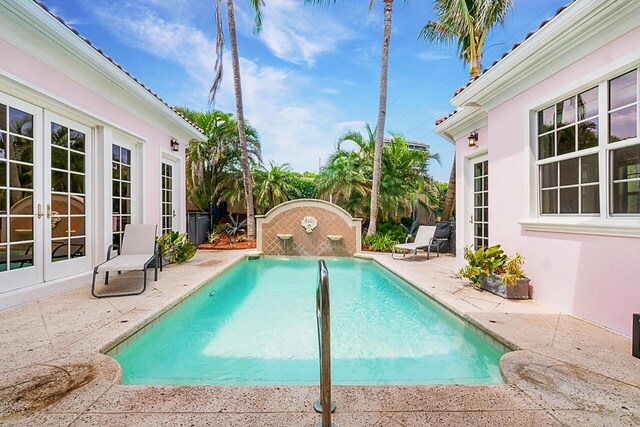 view of pool featuring pool water feature, french doors, and a patio