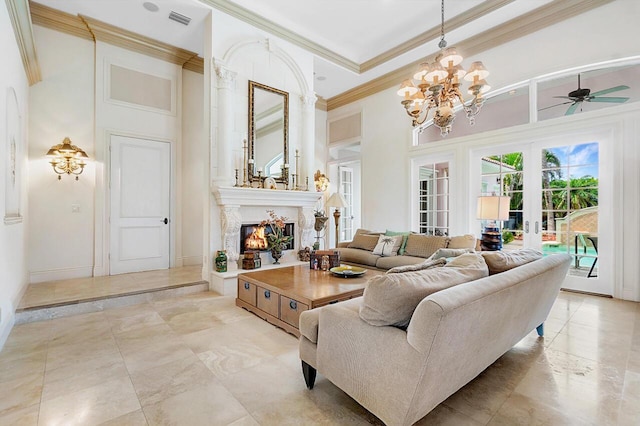 living room featuring french doors, a towering ceiling, ceiling fan with notable chandelier, crown molding, and a premium fireplace