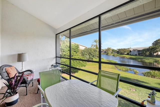 sunroom / solarium featuring a water view and lofted ceiling