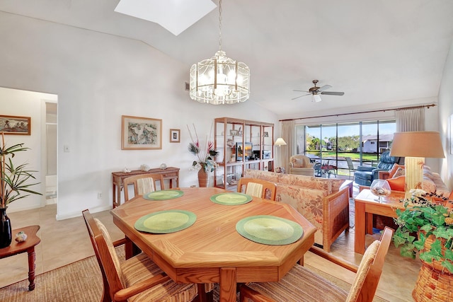 dining area featuring vaulted ceiling with skylight and ceiling fan with notable chandelier